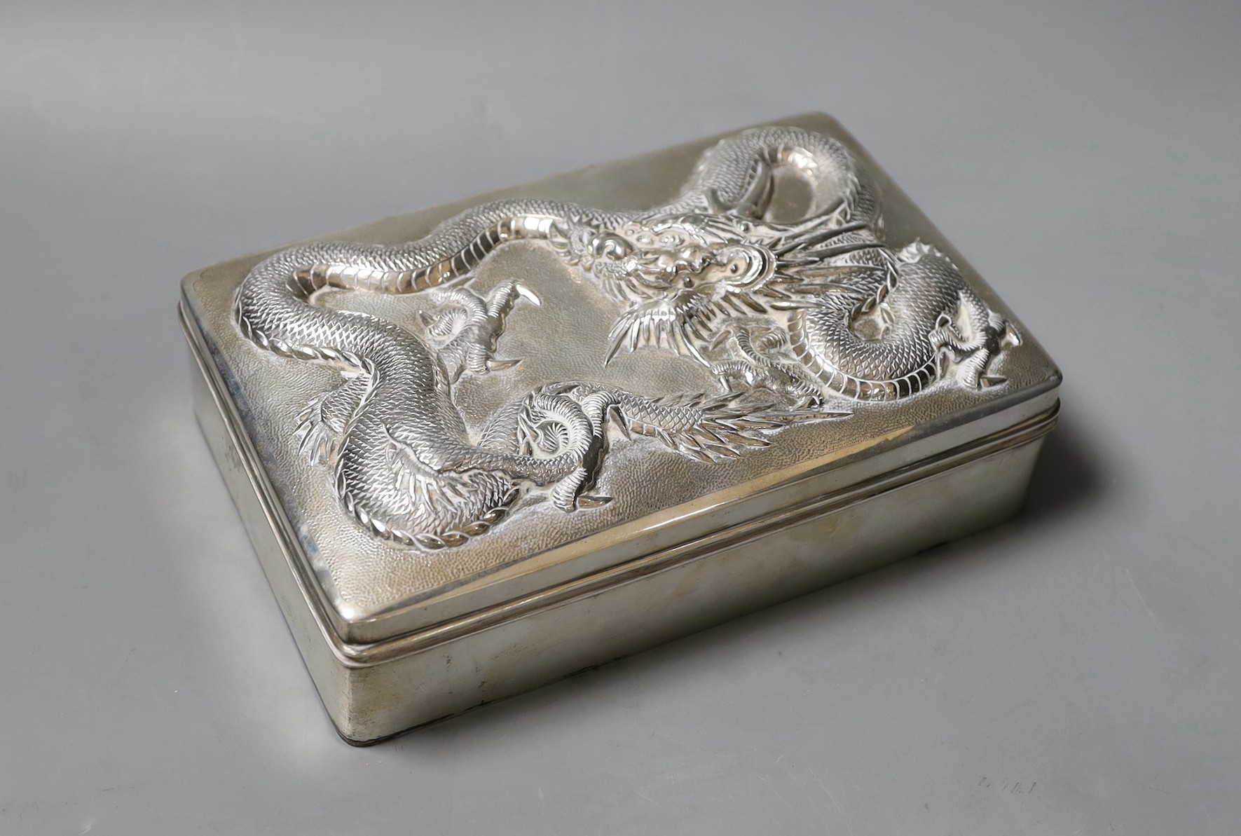 A Chinese Export white metal mounted cigarette box, by Wang Hing, Hong Kong, the lid decorated with a dragon, 21cm.